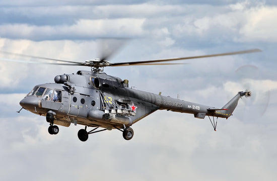 gray russian helicopter flies against a cloudy sky
