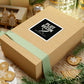 Wooden gift box with a 'Plot Recon' sticker on a festive background with cookies and greenery.